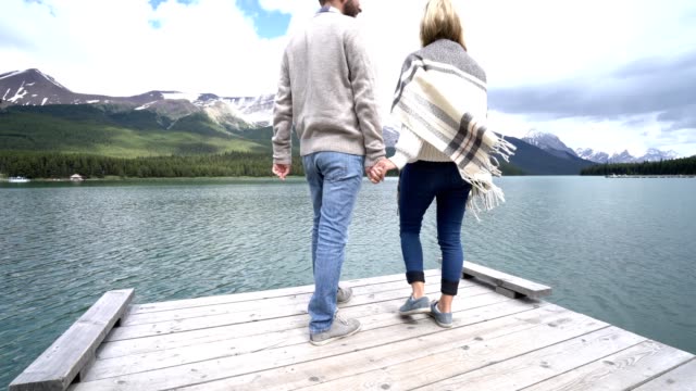Joven-pareja-relajarse-en-el-muelle-del-lago,-caminar-y-contemplar-vistas-Canadá