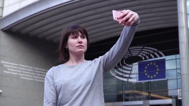 Turismo-de-mujer-toma-pictureson-smartphone-cerca-del-Parlamento-Europeo-en-Bruselas.-Bélgica