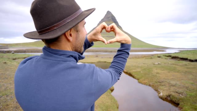 Hombre-joven-en-Islandia-que-marco-del-dedo-corazón-forma-a-la-famosa-montaña-de-Kirkjufell