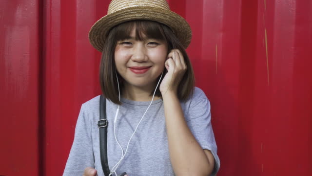 Hermosa-mujer-asiática-joven-escuchando-música-en-un-teléfono-inteligente-en-la-ciudad.-Mujer-asiática-joven-relajarse-escuchando-música-en-la-calle.