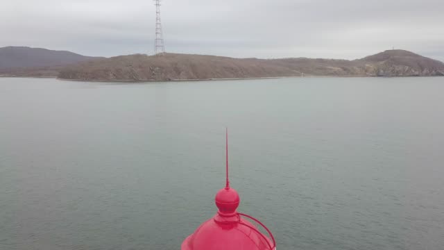 Ansicht-von-oben-rote-Dach-des-Leuchtturm-im-Meer-auf-Gebirgshintergrund