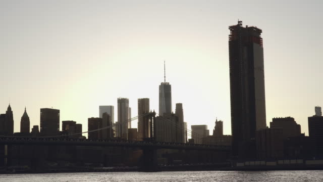 Ein-Blick-auf-die-Skyline-von-Lower-Manhattan-und-Brooklyn-Bridge-in-New-York,-Vereinigte-Staaten-von-Amerika-im-Sonnenuntergang-gefilmt-vom-East-River