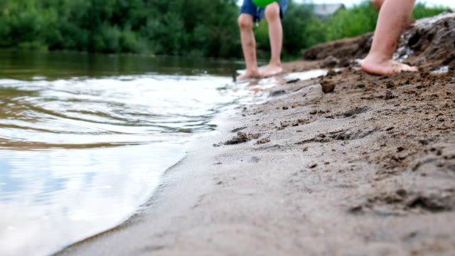 Blurred-childish-legs.-Children-playing-on-the-river-with-sand