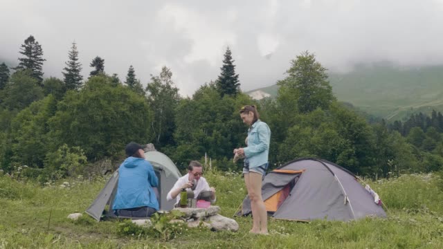 Freunde-im-Sommer-camping-ruht.-Menschen,-die-Ruhe-in-der-Nähe-von-camping-Zelt-im-Wald