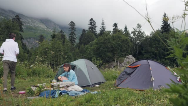 Tourist-couple-resting-on-camping-tent-in-mountain-landscape