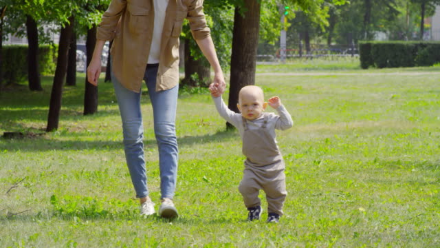Bebé-caminando-en-el-parque-con-madre