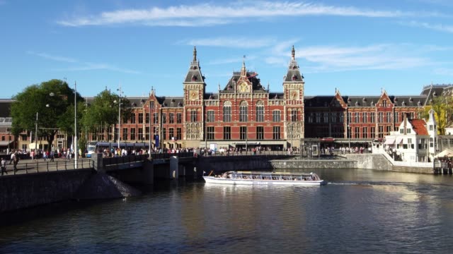 Barco-turístico-en-el-centro-del-canal-frente-a-la-estación-Central-de-Ámsterdam,-Europa.