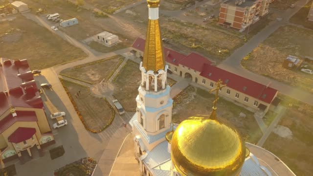 aerial-close-up-religion-cross-on-top-of-amazing-golden-church-architecture-during-sunset