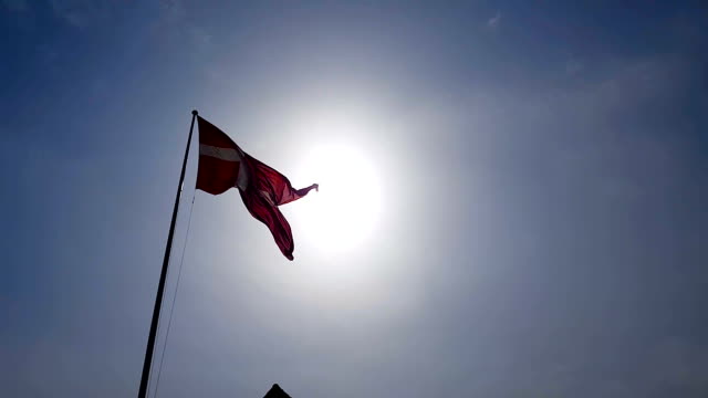 Denmark-flag-waving-in-sky-under-sunrays,-national-symbol,-patriotism-emblem