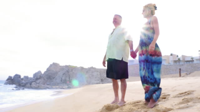 An-older-couple-holding-hands-and-looking-out-at-the-ocean