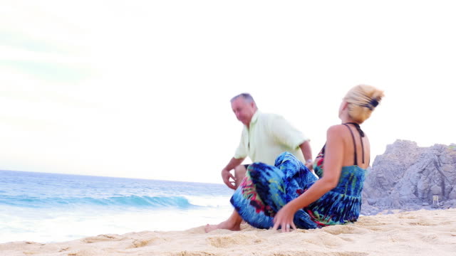 An-older-couple-sit-on-the-beach-and-watch-the-waves