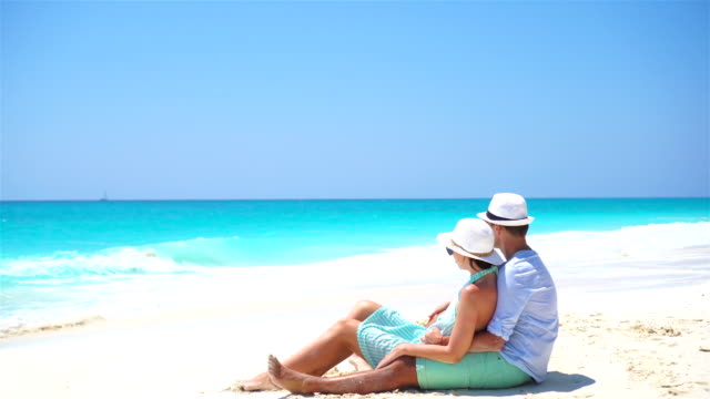 Young-couple-on-white-beach-during-summer-vacation.-Happy-lovers-enjoy-their-honeymoon.