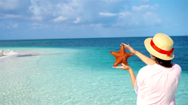 Young-woman-with-starfish-on-white-beach-in-the-nature-reserve