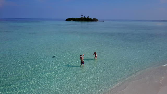 v03811-vista-aérea-de-drone-volador-de-playa-en-isla-paraíso-soleado-con-cielo-azul-aqua-mar-agua-océano-4k-2-personas-pareja-hombre-mujer-tocando-juntos-diversión-bola-blanco-Maldivas