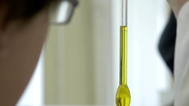 Primer-plano-del-tubo-de-vidrio-con-líquido-azul-en-la-mano-del-científico-durante-el-examen-médico.-los-científicos-de-la-mano-sosteniendo-un-tubo-de-ensayo-con-líquido-químico-verde.-Dedos-de-científico-con-un-tubo-de-vidrio-en-un-laboratorio-de-investigación
