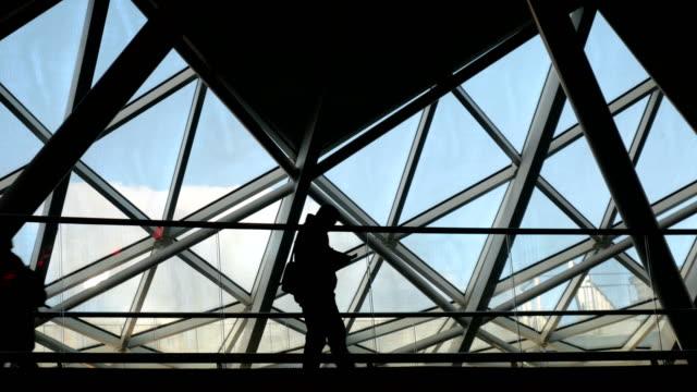 Man-using-a-phone-silhouetted-against-a-contemporary-architectural-background.