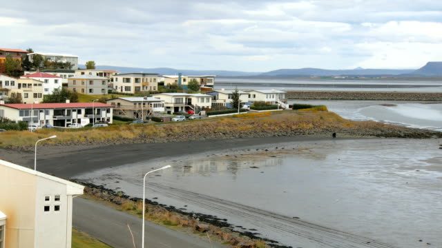 outskirts-of-small-icelandic-town-with-living-houses,-river-and-mountains-are-in-background