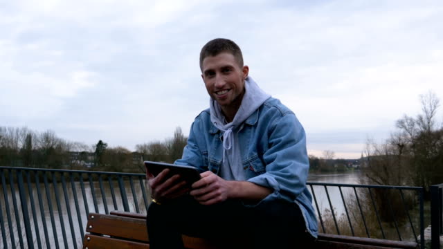 Porträt-einer-glücklichen-Mann-Lesung-auf-einem-digitalen-Tablet-in-der-Natur