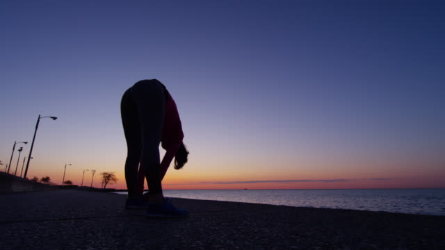 Flexible-Hispanic-Caucasian-female-silhouette-stretching-at-sunrise