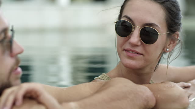 Couple-in-Sunglasses-Chatting-in-Swimming-Pool