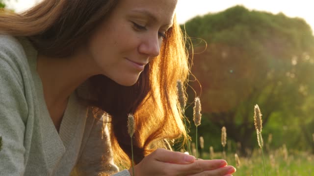 Retrato-de-mujer-tocando-la-hierba-en-el-campo-de-luz-de-sol-de-oro