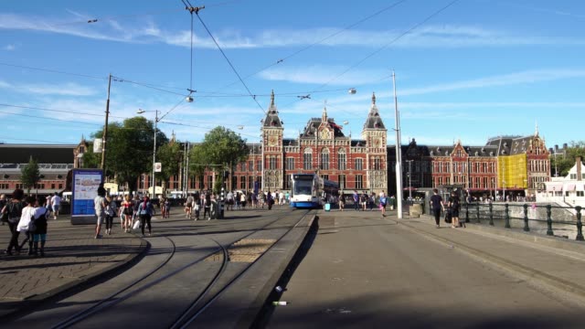 Tram-departs-the-Central-Railway-Station-in-Amsterdam,-Europe.