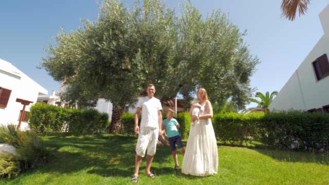Junge-Familie-mit-zwei-Kindern-in-der-Nähe-von-Olivenbaum-im-Garten