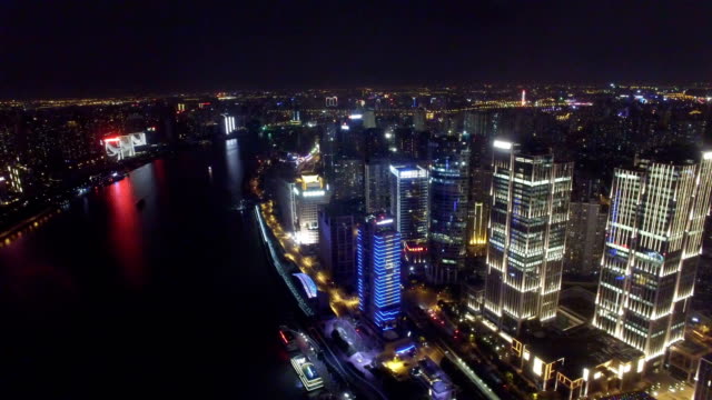 Toma-aérea-de-nave-corriendo-en-el-río-Huangpu-en-la-noche-de-Shanghai,-China