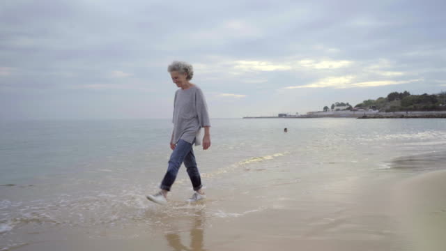 Beautiful-senior-woman-splashing-around-sea-water.