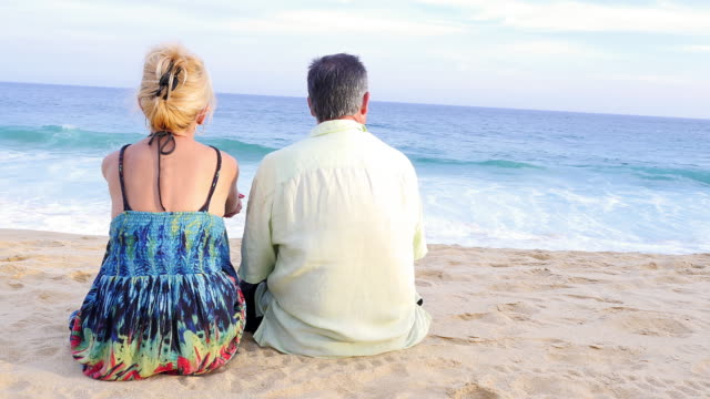 An-older-couple-sitting-on-the-beach-and-watching-the-waves