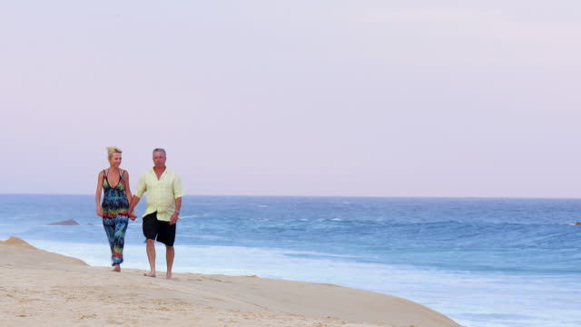Una-Pareja-de-ancianos-sosteniendo-las-manos-y-caminar-en-la-playa