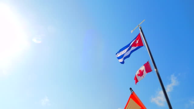 4K-Cuba-and-Canada-Flag,-Tourists-Relax-on-Tropical-White-Sand-Beach