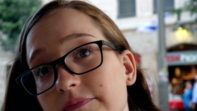 Teenager-Mädchen-mit-Brille-singen-und-schaut-an-der-Kamera,-städtisches-Motiv,-Stadtleben-Hintergrund