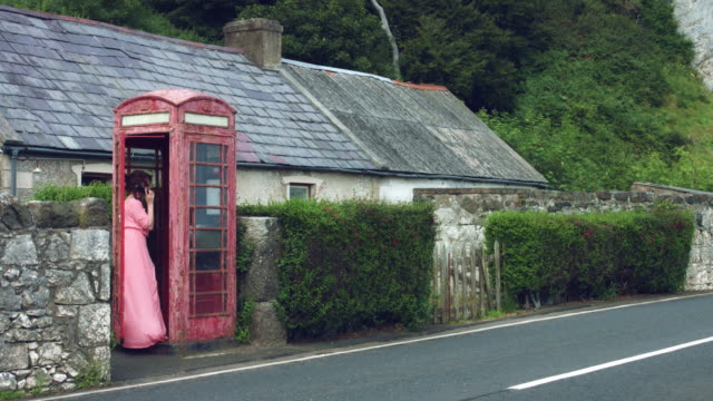 4k-schoss-einer-Frau-posiert-in-eine-rote-Telefonzelle,-Vereinigtes-Königreich