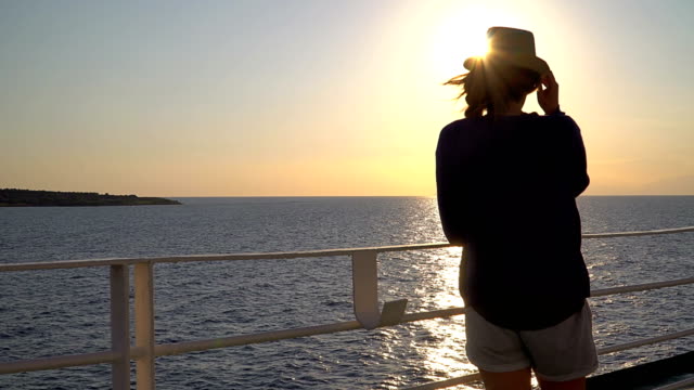 Silueta-de-mujer-atractiva-joven-viendo-la-puesta-de-sol-en-barco-de-crucero-en-el-mar