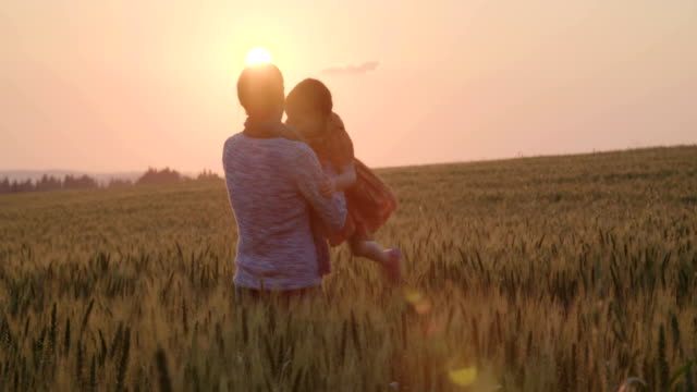 young-Asian-family-in-a-field-with-a-baby-1-year-on-hand,-the-concept-of-family-happiness,-beautiful-sunlight,-sunset,-slow-motion