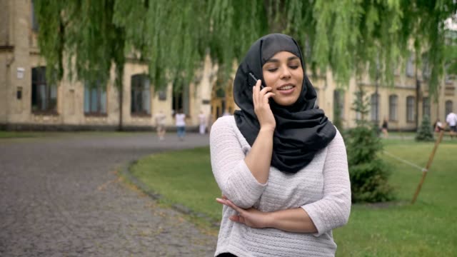 Junge-muslimische-Frau-Hijab-ist-telefonieren-und-lächelnd-in-blauen-Wetter,-aufbauend-auf-Hintergrund,-Religiuos-Konzept,-Kommunikations-Konzept