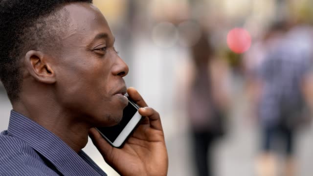 Lächelnde-junge-afrikanische-Amerikaner-sprechen-per-Telefon-in-der-Straße-Profil