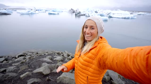4K-Young-woman-taking-selfie-with-glacier-lake,-icebergs-floating-on-water