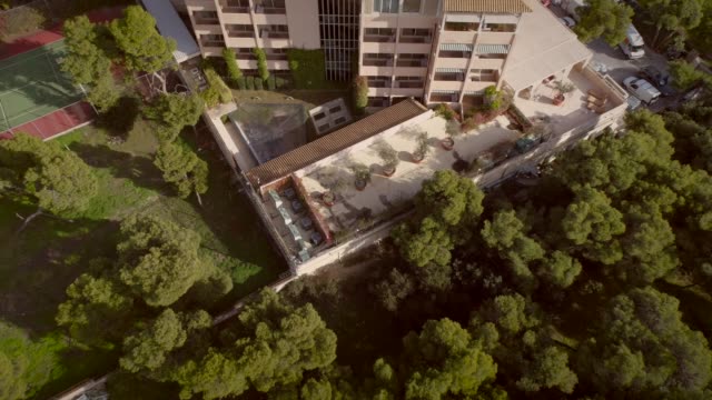 Vista-aérea-de-un-edificio-residencial,-rodeado-de-árboles-en-Grecia.