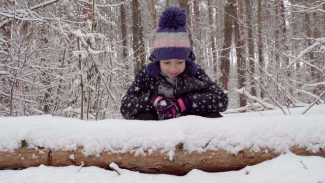 Girl-sitting-behind-a-fallen-tree-in-the-woods-4K