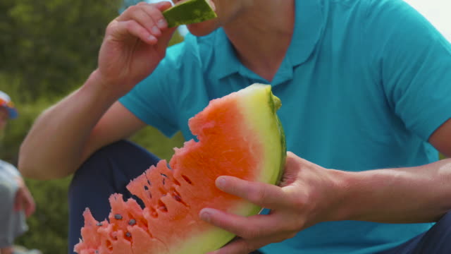 Man-eating-fresh-sweet-watermelon-outdoors,-close-up-crace-shot