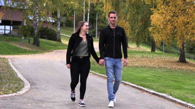 Young-guy-with-a-girl-walk-in-the-park,-holding-hands