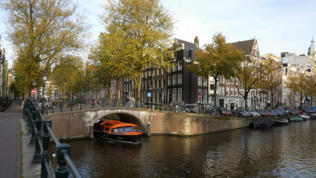 Orange-Ausflugsboot-Unterquerung-einer-Kanalbrücke-in-amsterdam