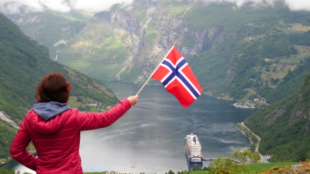 Tourist-with-norwegian-flag-and-cruise-ship-on-fjord