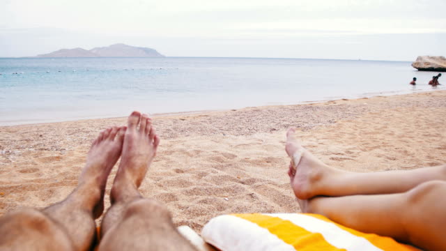 Legs-of-People-Lying-on-Beach-Sun-Lounger-near-the-Sea