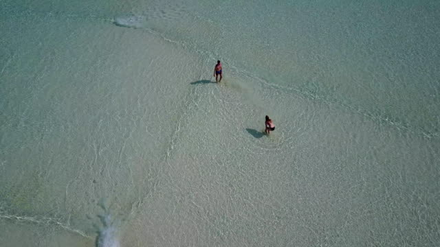 v03806-vista-aérea-de-drone-volador-de-playa-en-isla-paraíso-soleado-con-cielo-azul-aqua-mar-agua-océano-4k-2-personas-pareja-hombre-mujer-tocando-juntos-diversión-bola-blanco-Maldivas