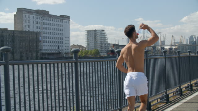 A-Very-fit-young-man-running-shirtless-though-London,-England's-Docklands.