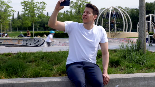Bogen-um-ein-Mann-sitzt-in-einem-Park-mit-einem-Smartphone-Dreharbeiten