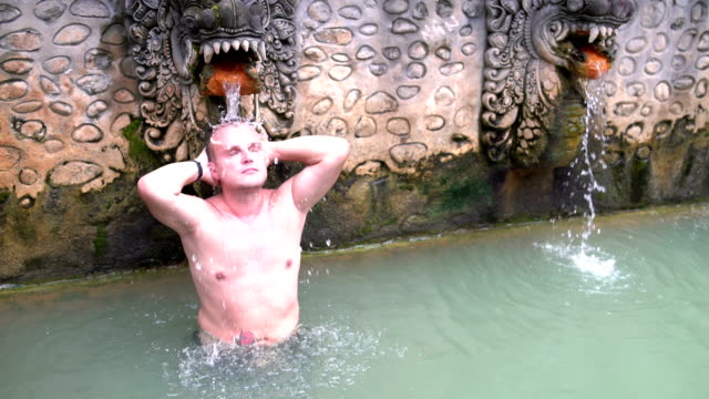 Ein-Mann-in-einem-Badeanzug-steht-unter-einen-Strom-von-Wasser-in-einem-Pool-mit-Wasserstoff-sulfide-Wasser
